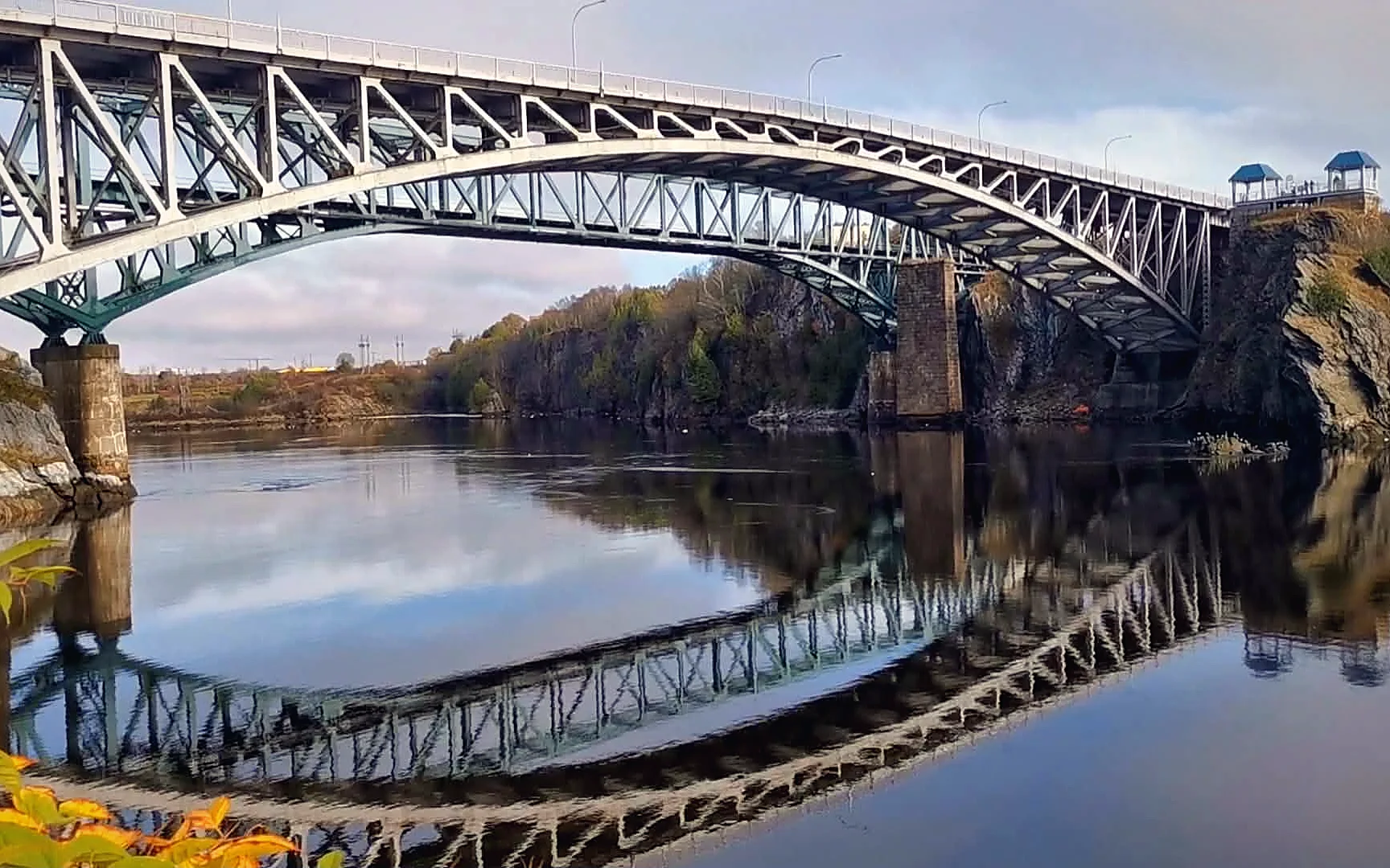 Arched steel bridge reflected in calm water at Reversing Falls