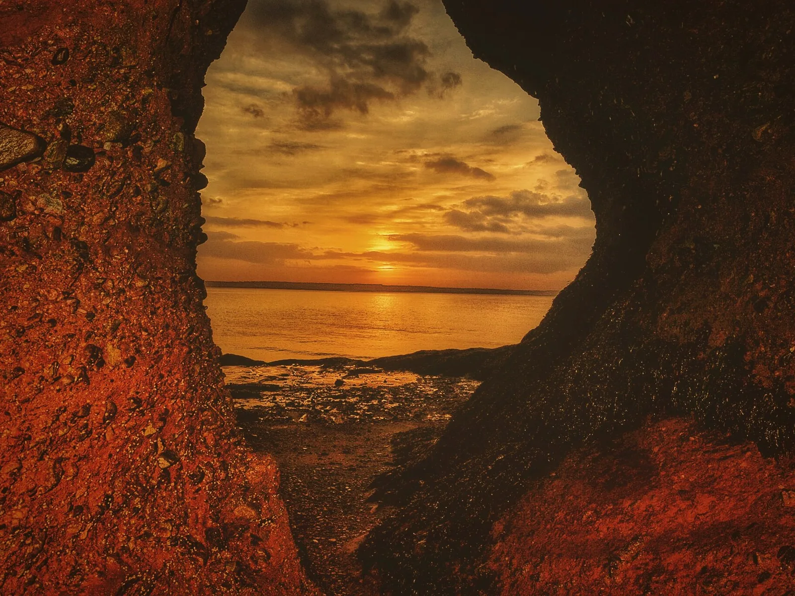 Sunrise seen through a sandstone arch at Hopewell Rocks